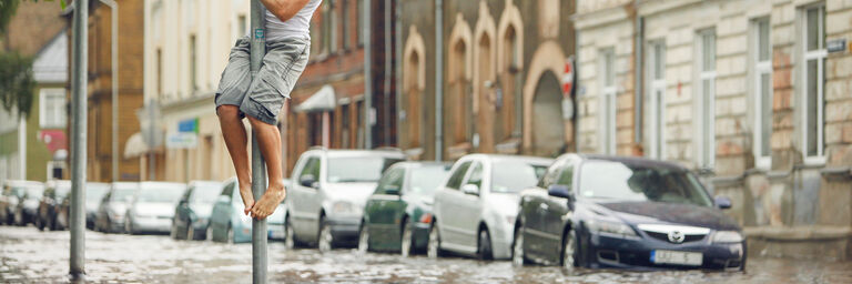Flooded street with a man who climbed on a road sign to stay dry.