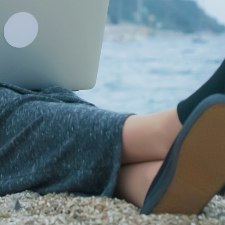 Feets on beach, with laptop.