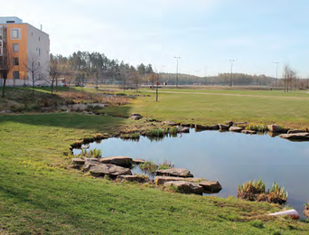 Picture of a lake in a residential area, apartment building to the left.