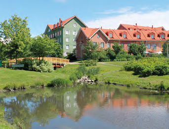 Apartment buildings behind a lake and green areas.