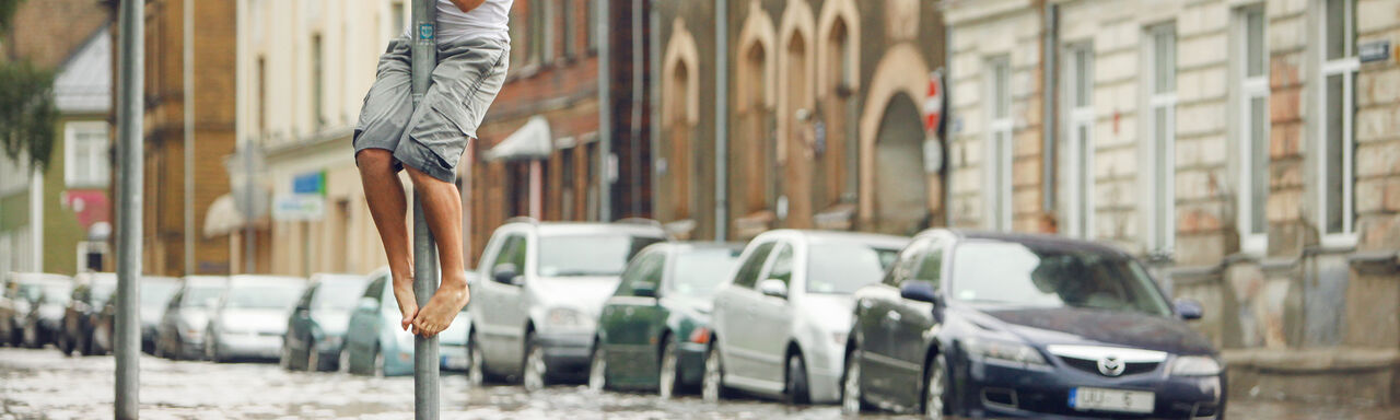 Flooded street with a man who climbed on a road sign to stay dry.